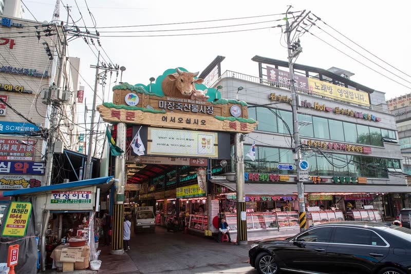 The entrance gate of Majang-dong's meat market and food alley in Seoul, with butcher shops along the street