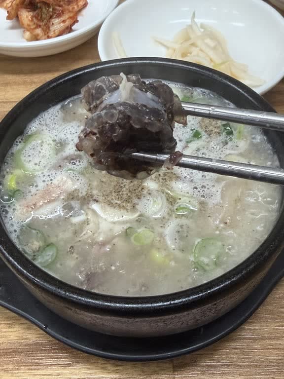 Chopsticks lifting a dark slice of old-style sundae from the soup